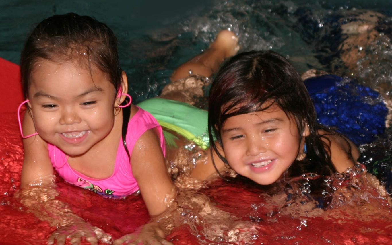 A Child and Youth Care First Nations Worker taking care of two little girls who are having fun at the pool