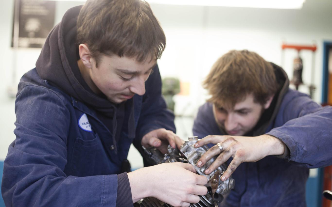 Students of the Marine Technician and Motorcycle Mechanic program repairing an engine